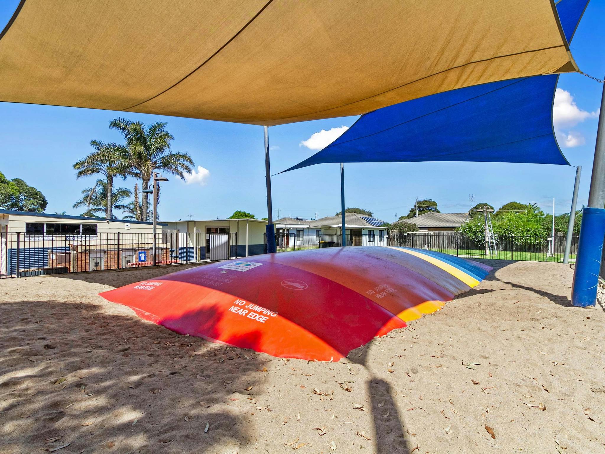 Colourful Jumping Pillow for Children, shaded by blue and orange shade cloth