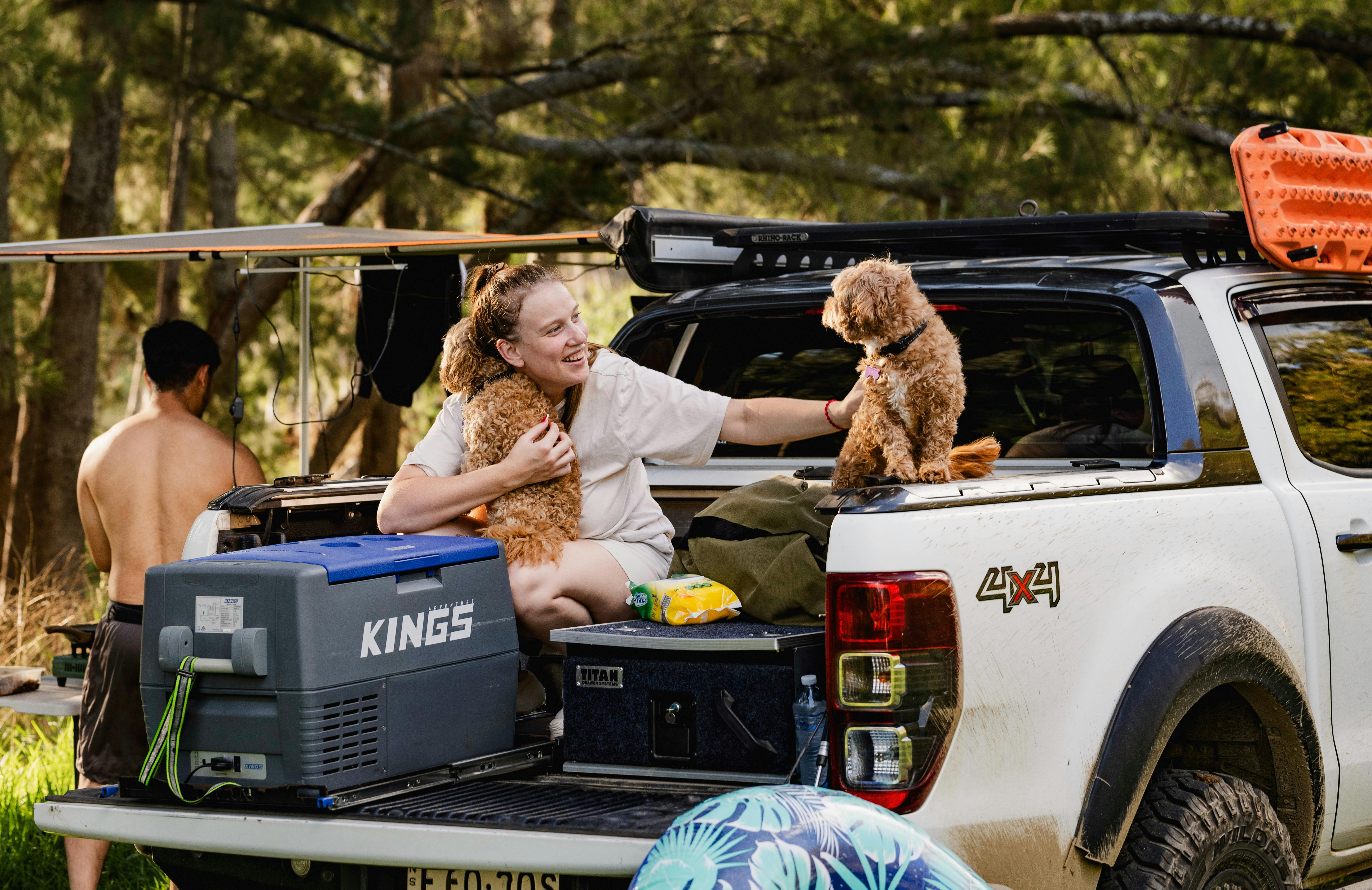 a couple and their dogs unpack their trailer for camping