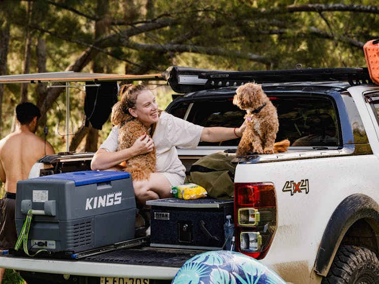a couple and their dogs unpack their trailer for camping