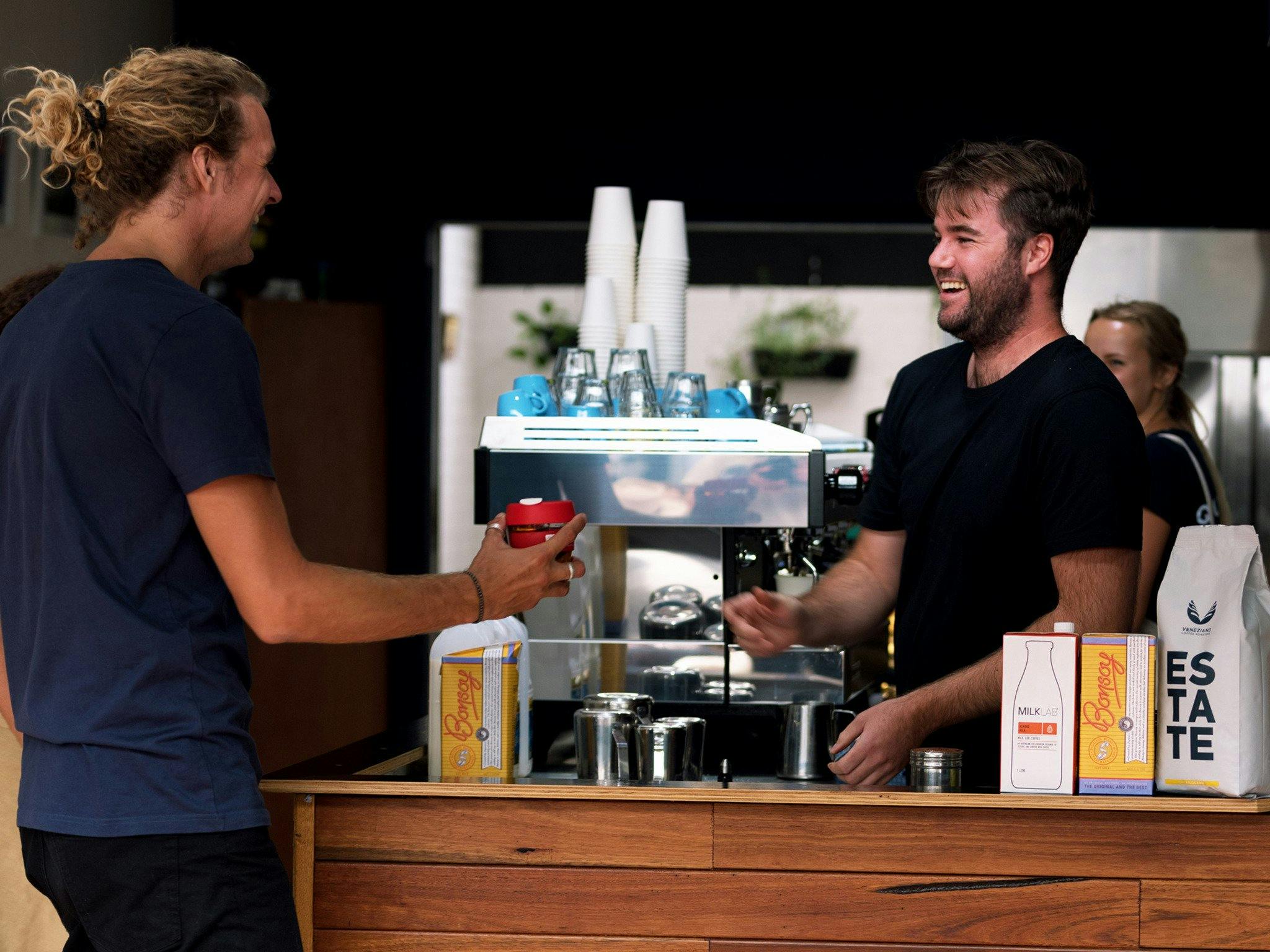 Barista handing customer coffee at Brennans cafe