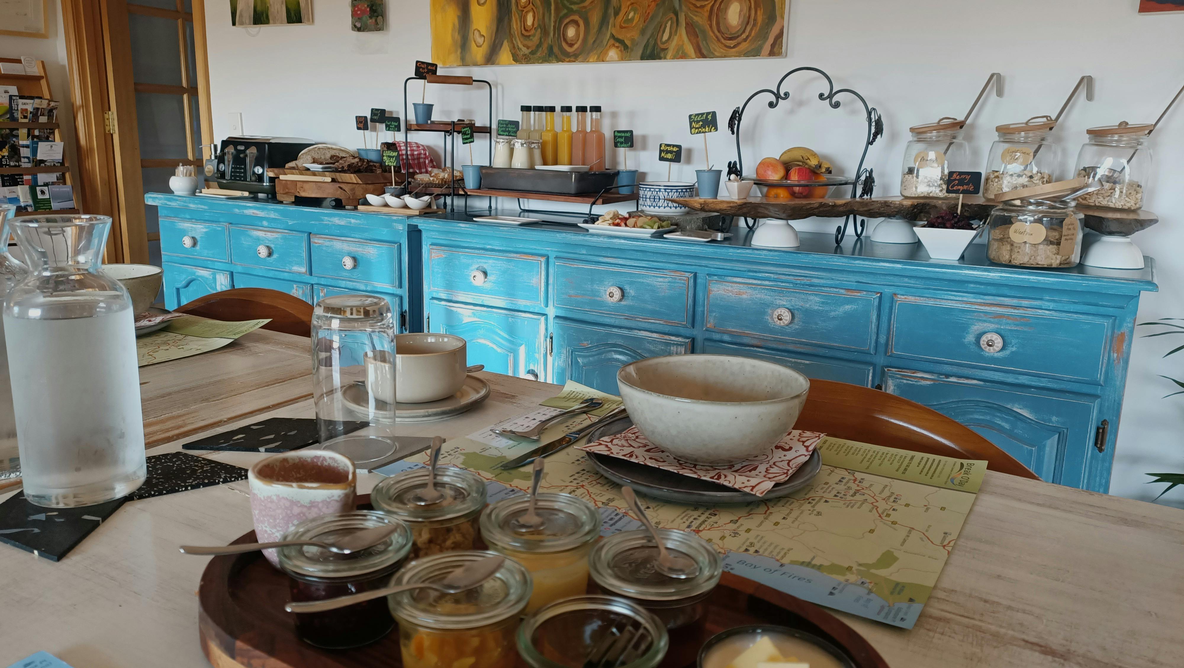 Tables set for breakfast with home-made jams and condiments and an array of cereals, bread and fruit