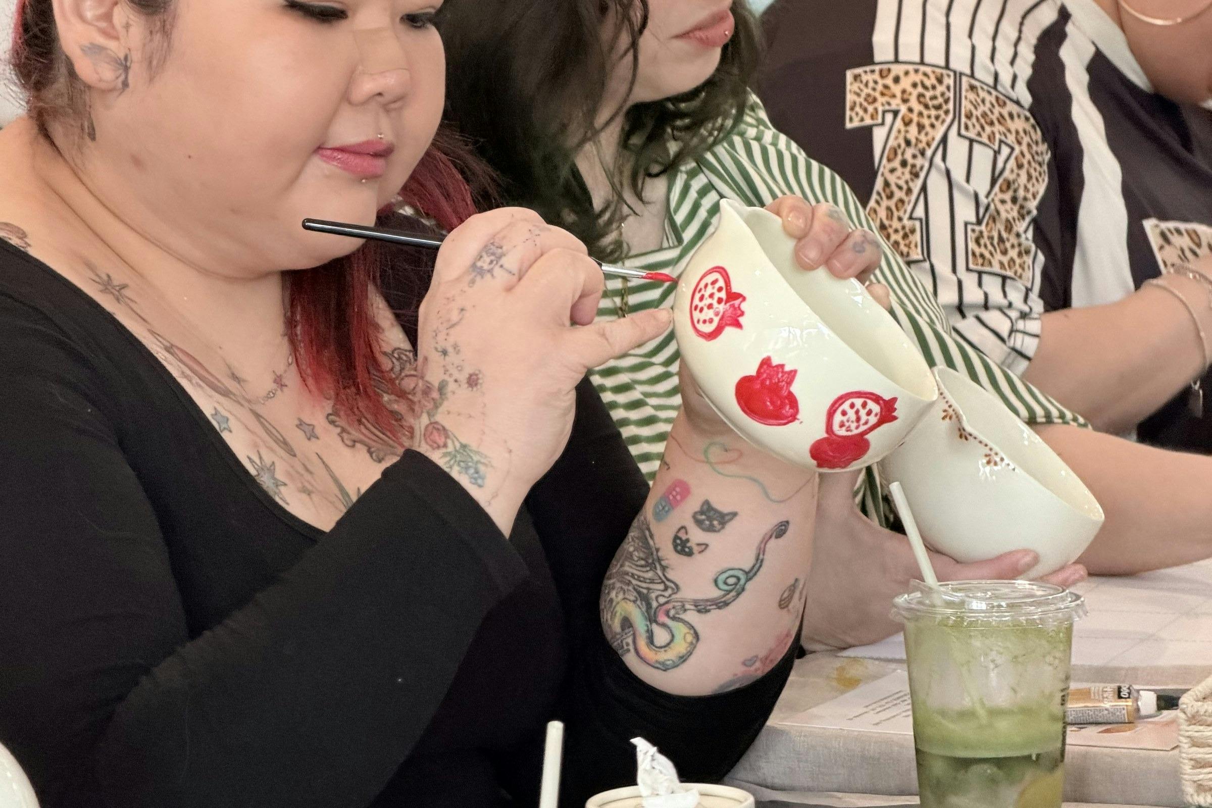Guest hand-painting a ceramic cup at a NOA Matcha workshop