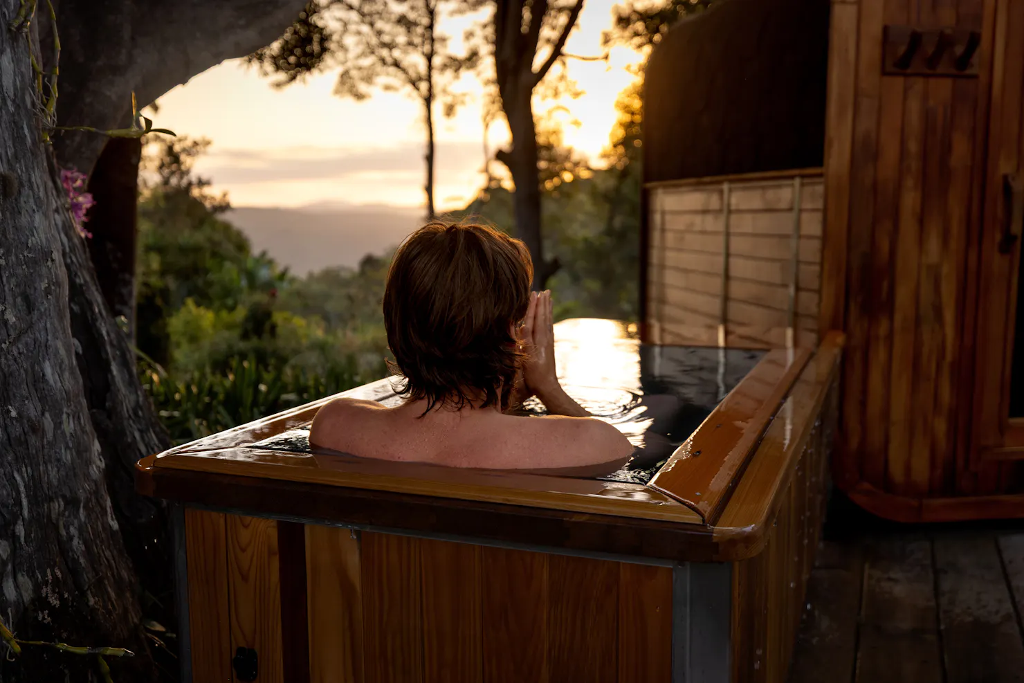 Person relaxing in the outdoor cold plunge overlooking the Sunshine Coast Hinterland.