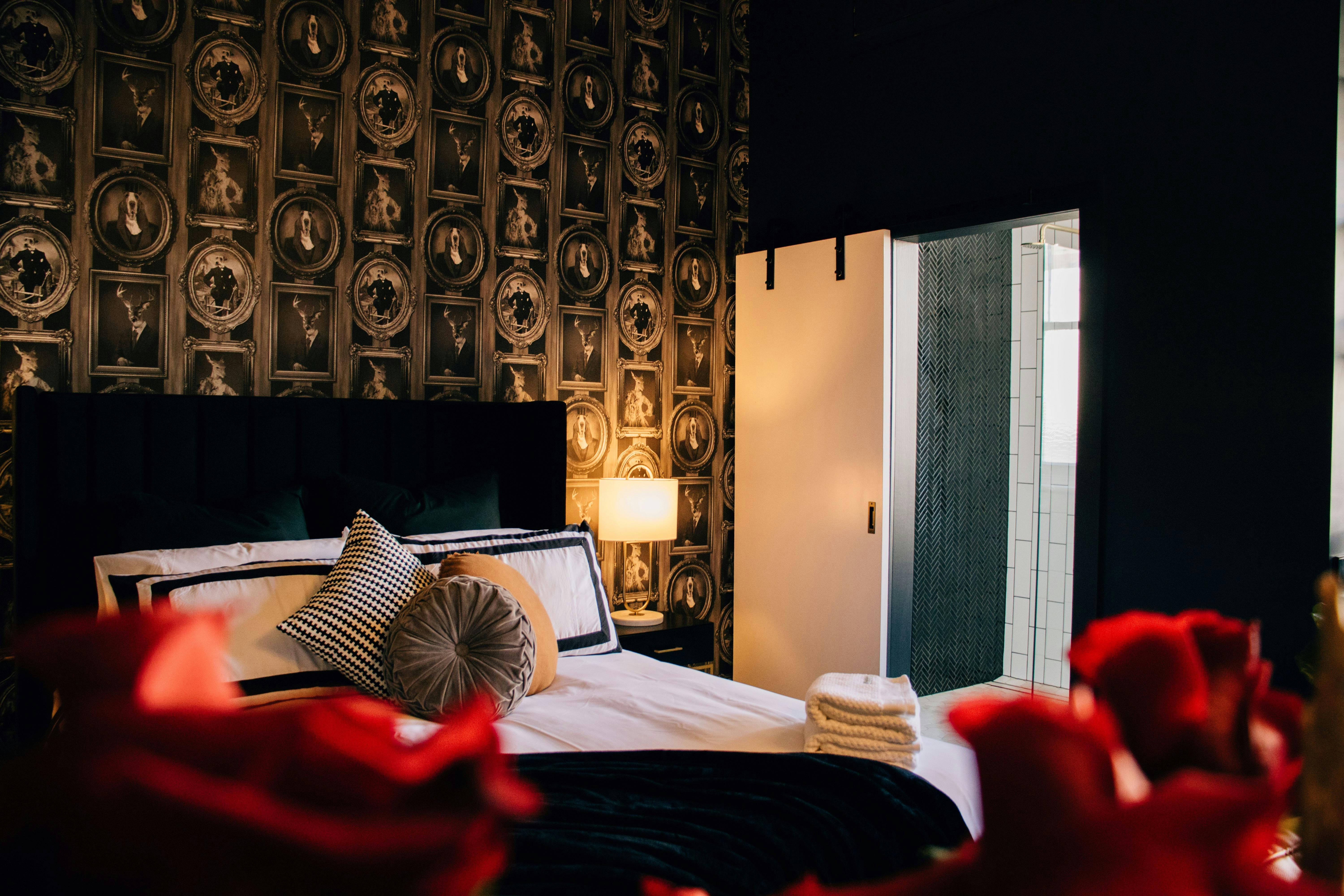 A queen bed with black and white linen and roses in the foreground.