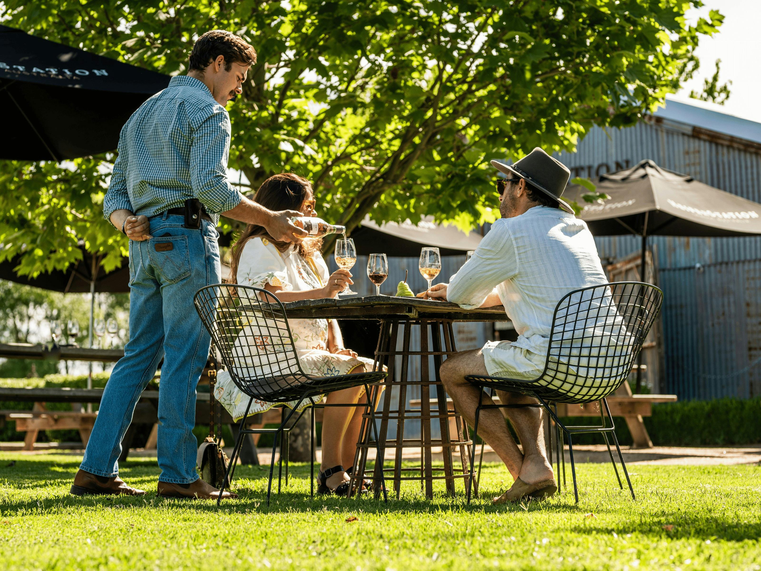 밖에 앉아 있는 두 사람과 와인을 따르는 서버