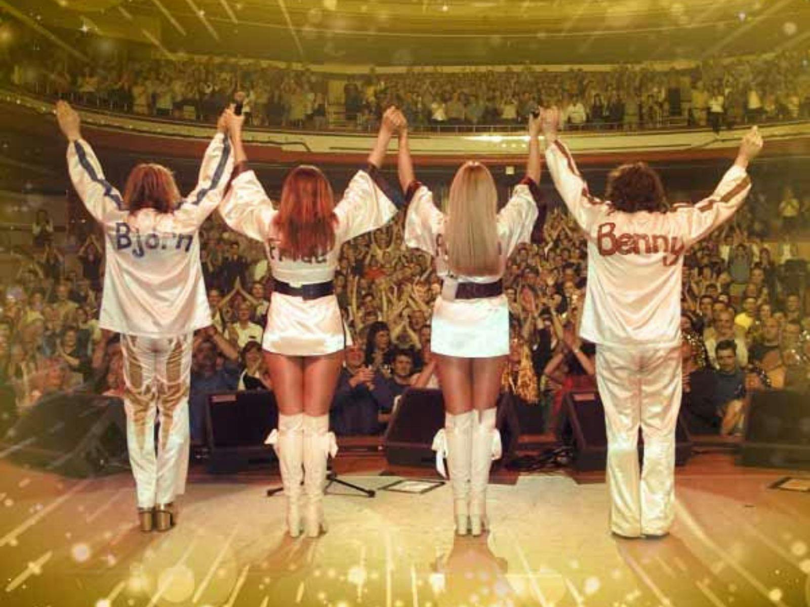 Four members of Bjorn Again facing an audience with their arms up