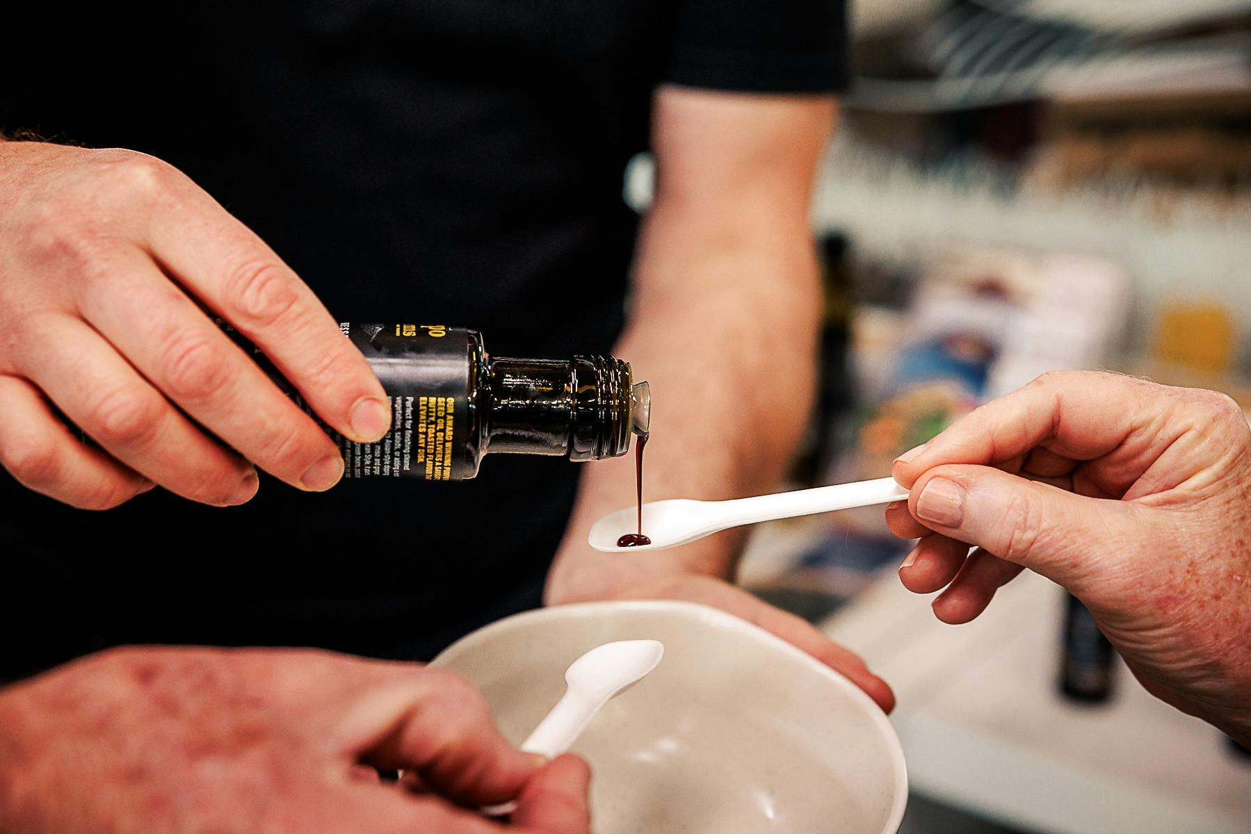 Pumpkin seed oil being poured onto spoons for sampling by guests