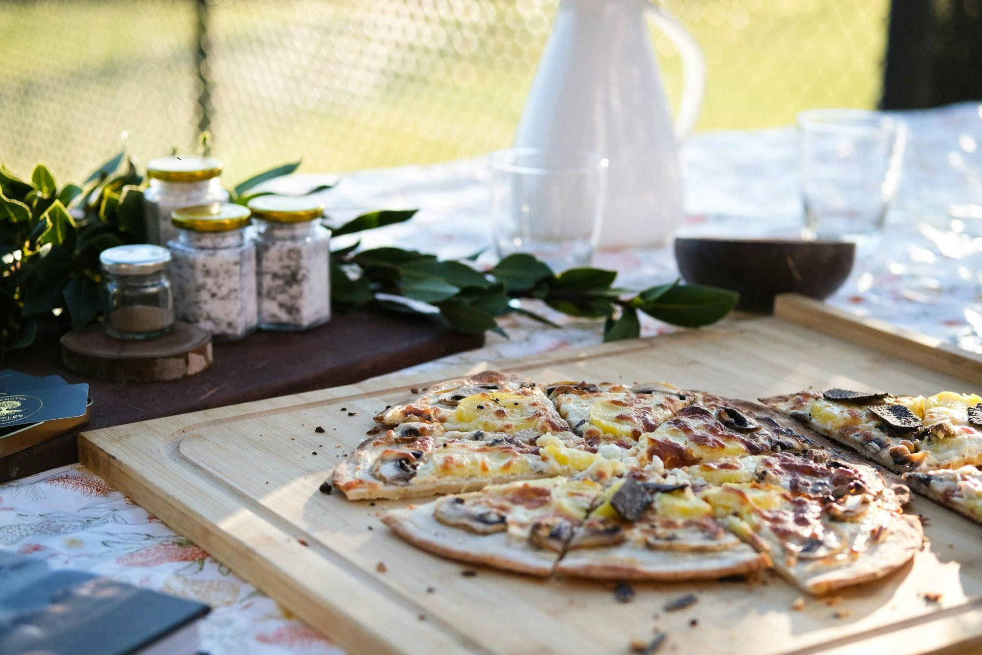 Pizza with truffle slices on top on wooden board, truffle products in background