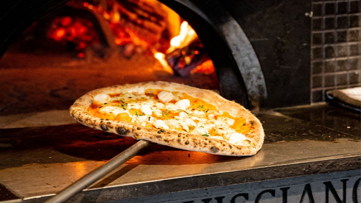 Woodfired pizza coming out of the oven