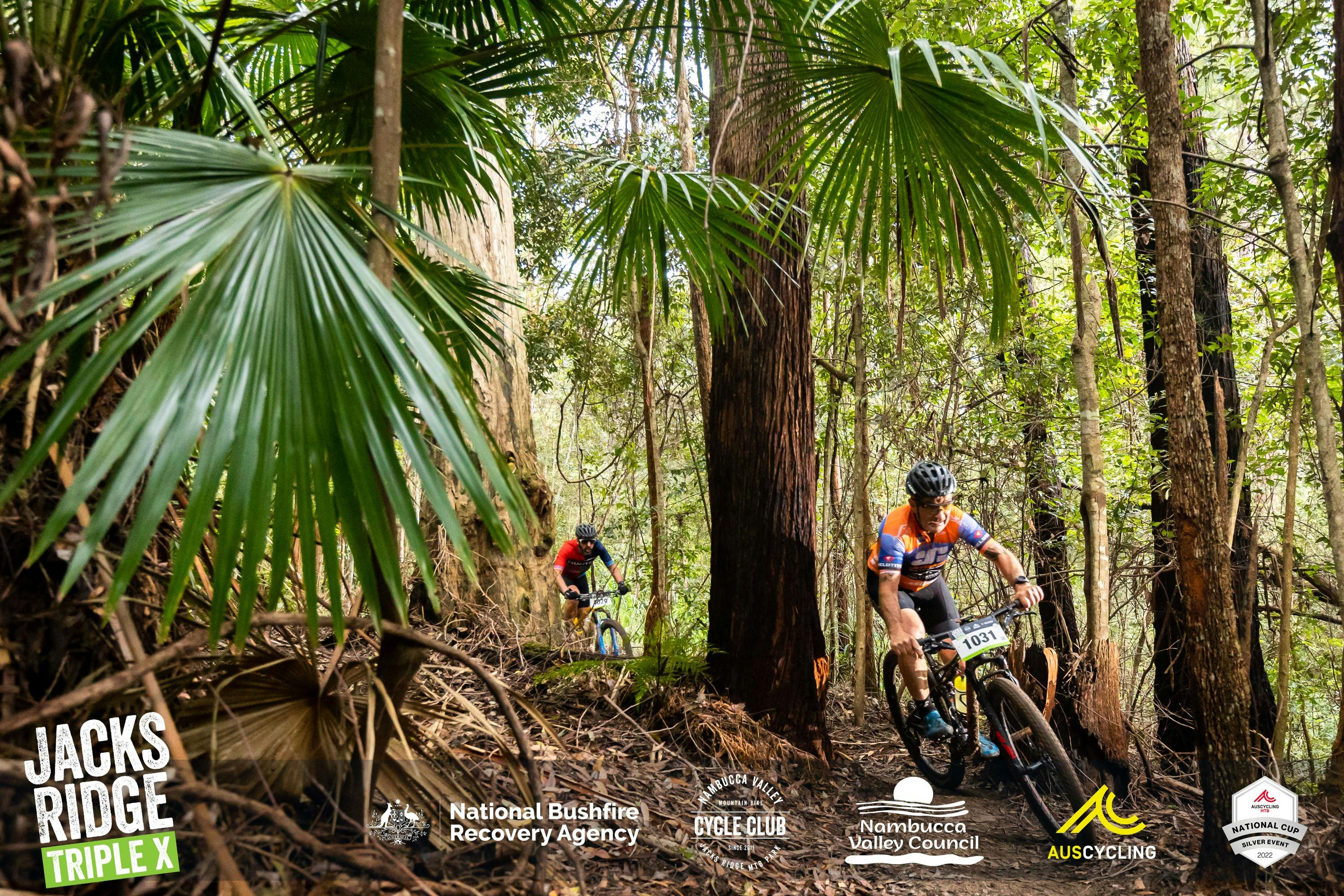 2 guys on mountain bikes hooning through a bush track surrounded by palms