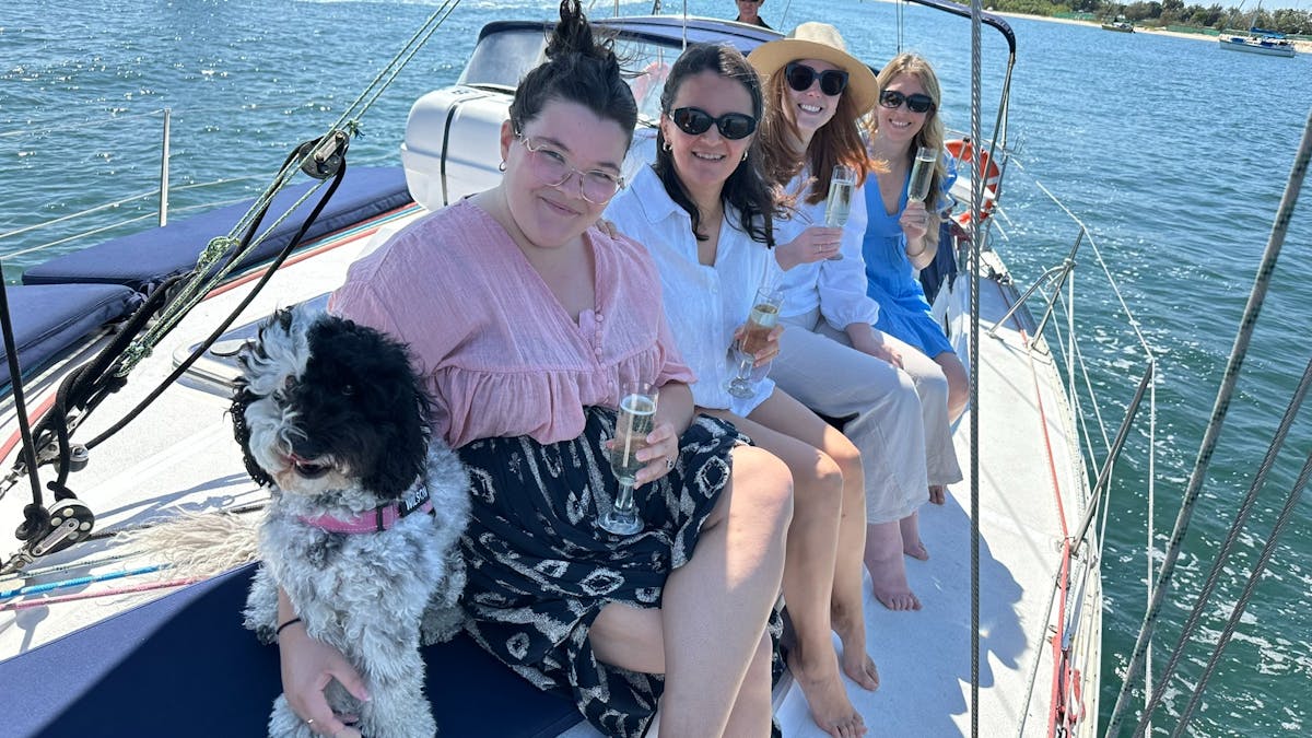 Four women sitting on yacht enjoying a sparkling wine with Spoodle during a Sun Sailing charter