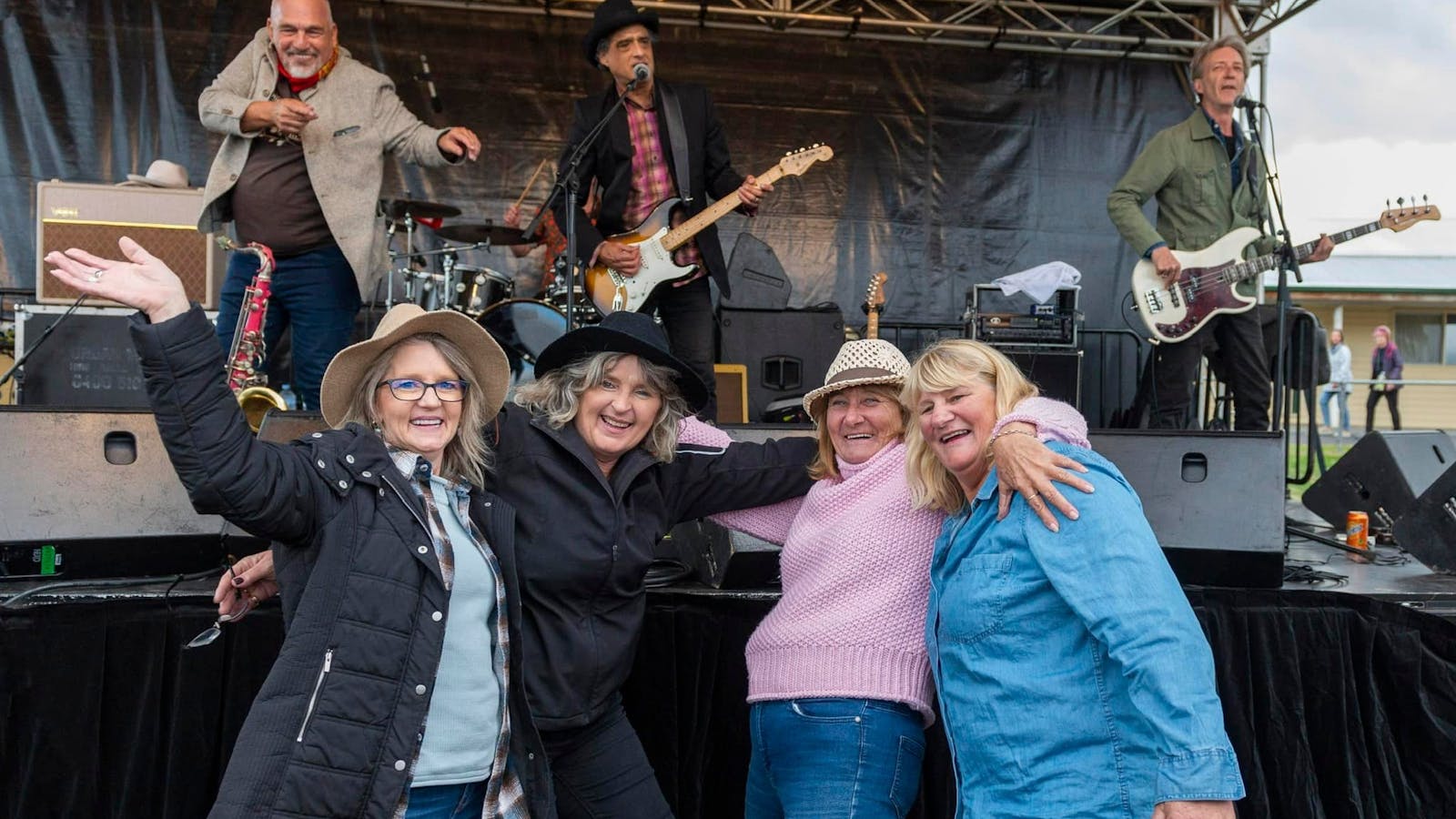 Four visitors posing in front of the music stage having fun.
