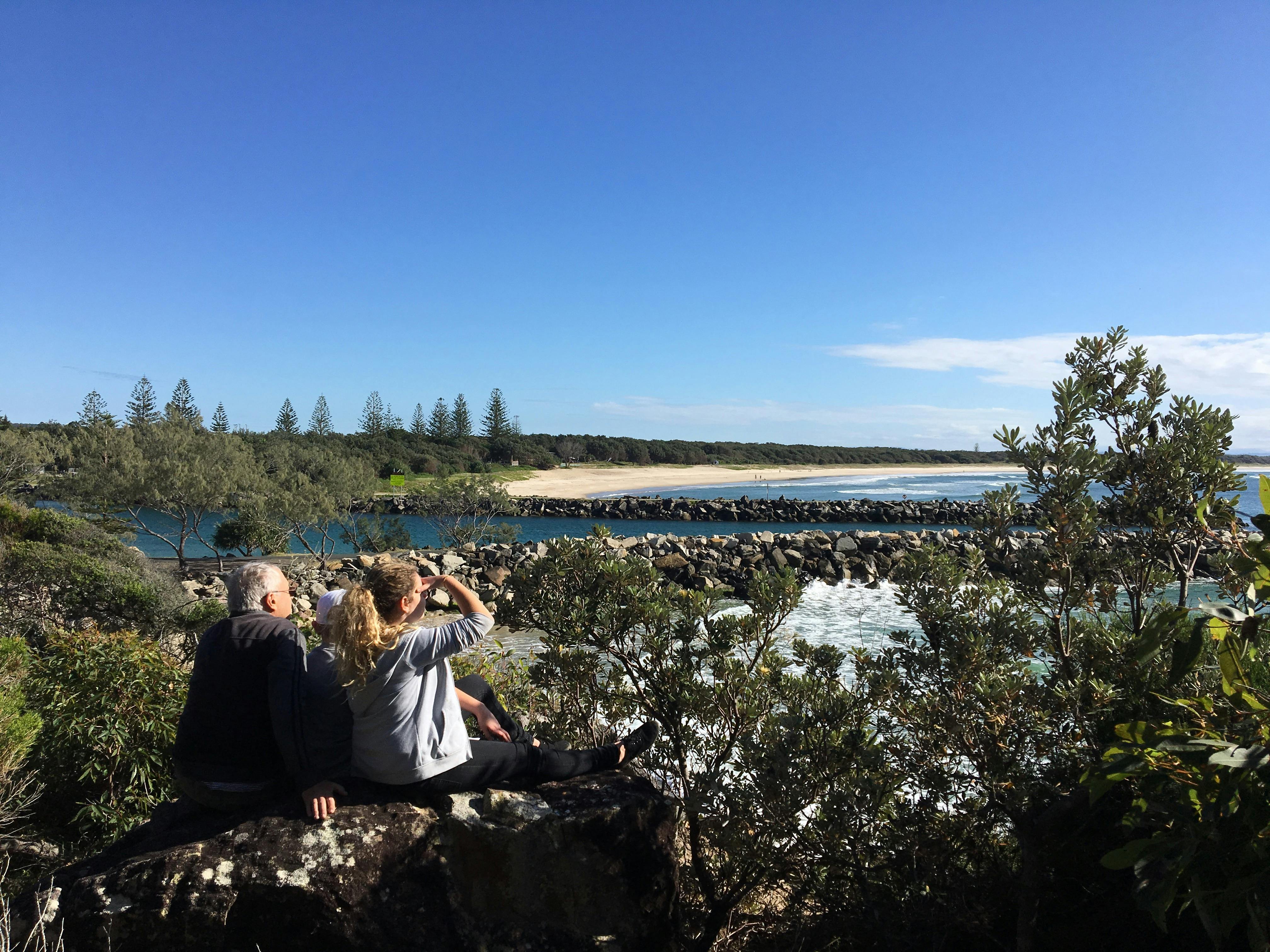 Couple sitting on a rock with the ocean in the background.