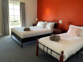 Queen bed and a single bed in a room with an orange wall