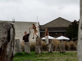 Family playing on posts at reserve with buildings in the background
