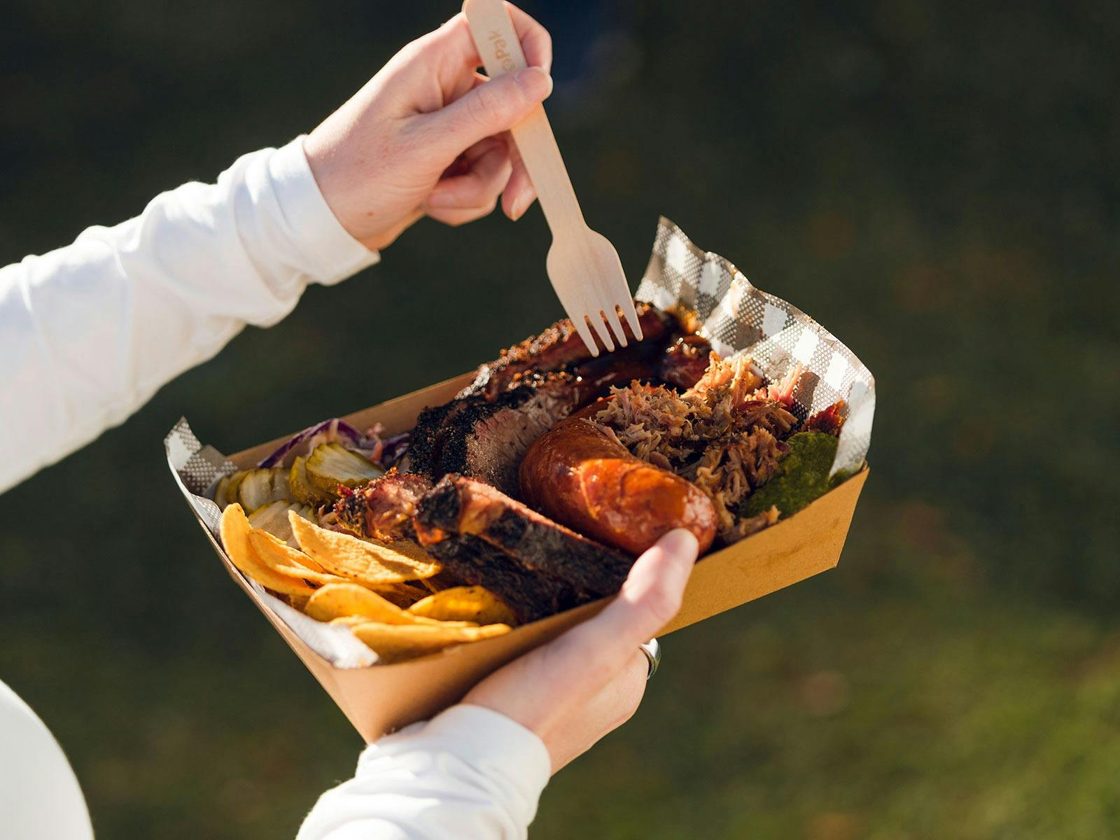 Person holding a tray with meat and chips