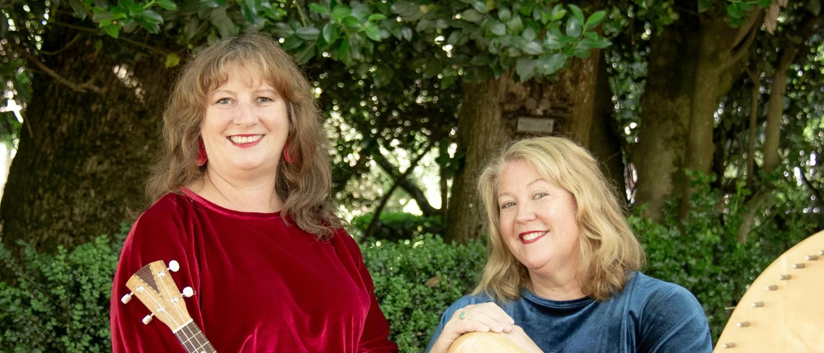 Two women smiling and holding a guitar