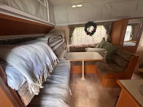 Two bunk beds with throw rugs, next to the L-shape dinette