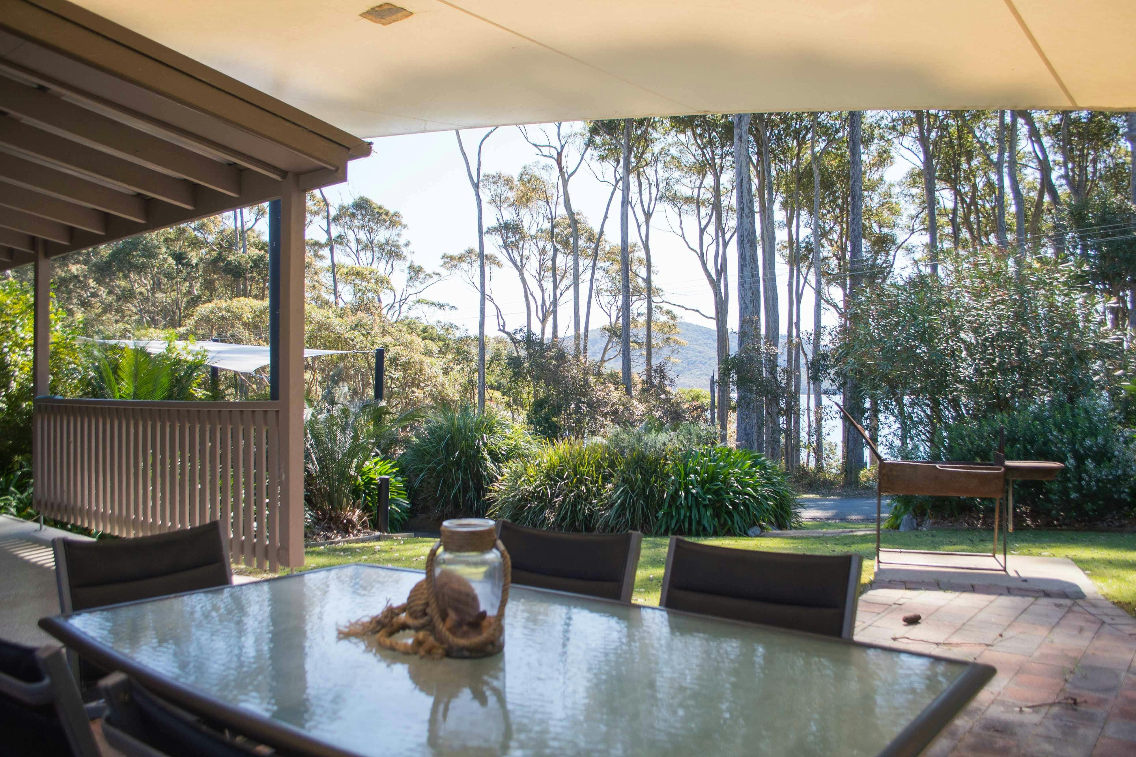 Deck & large outdoor BBQ area is shaded by a canvas sail and is set in a tropical landscaped garden