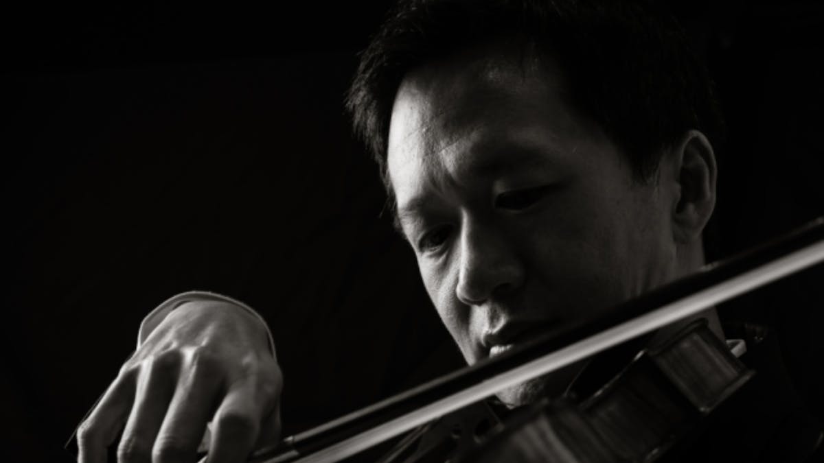 Black-and-white portrait of a violinist in profile, looking toward the light