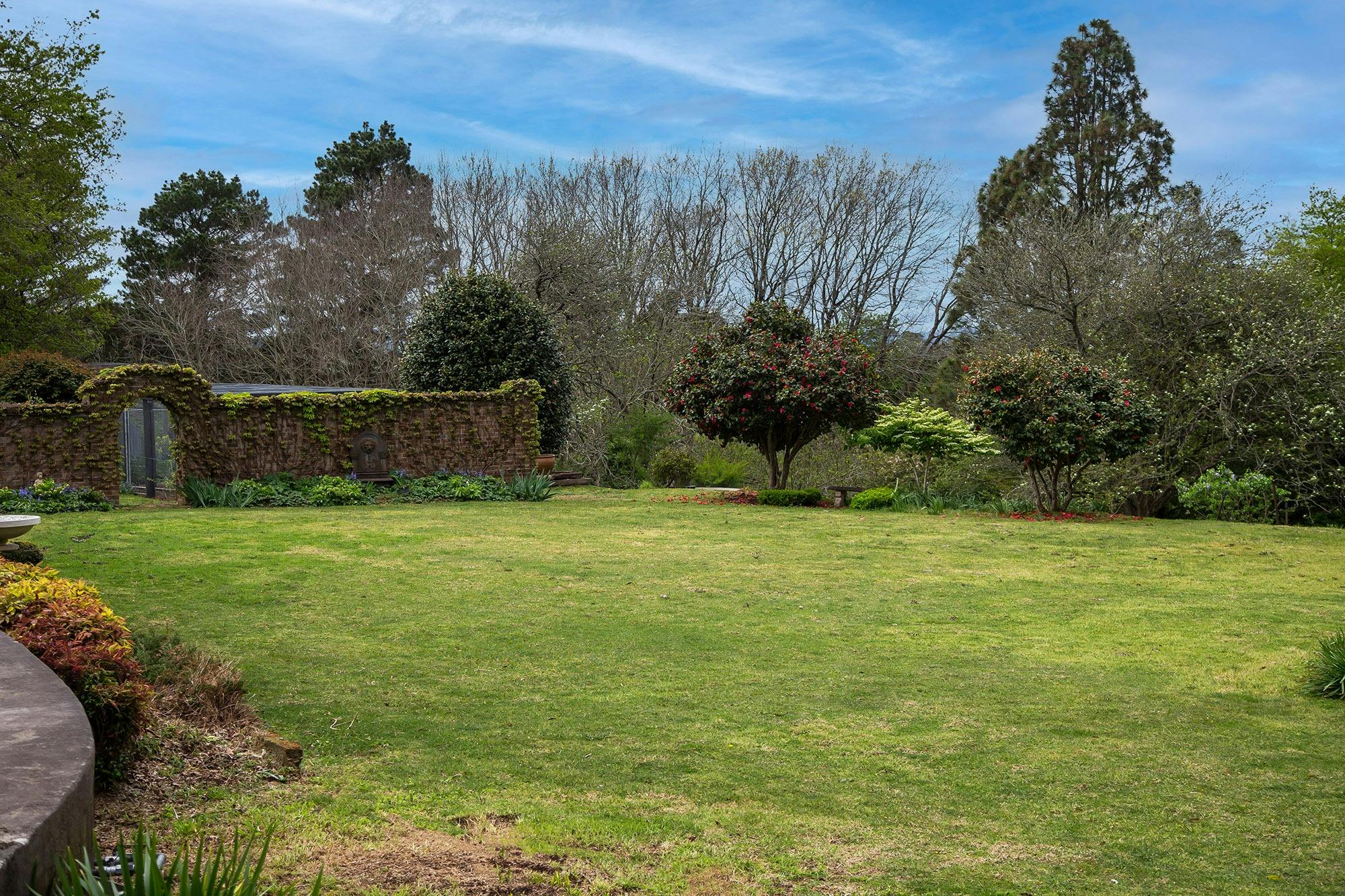 View across lawn to walled garden with trees