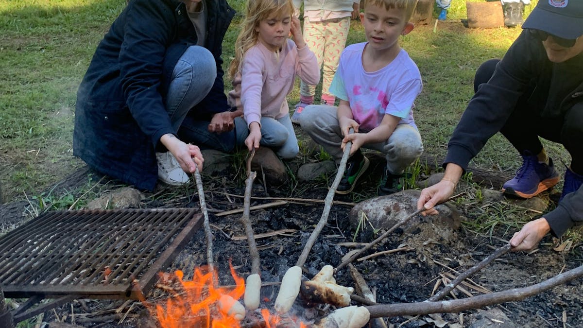 Families making damper on a stick at a campfire at the Family Campfire Cookout Families making damper on a stick at a campfire at the Family Campfire Cookout
