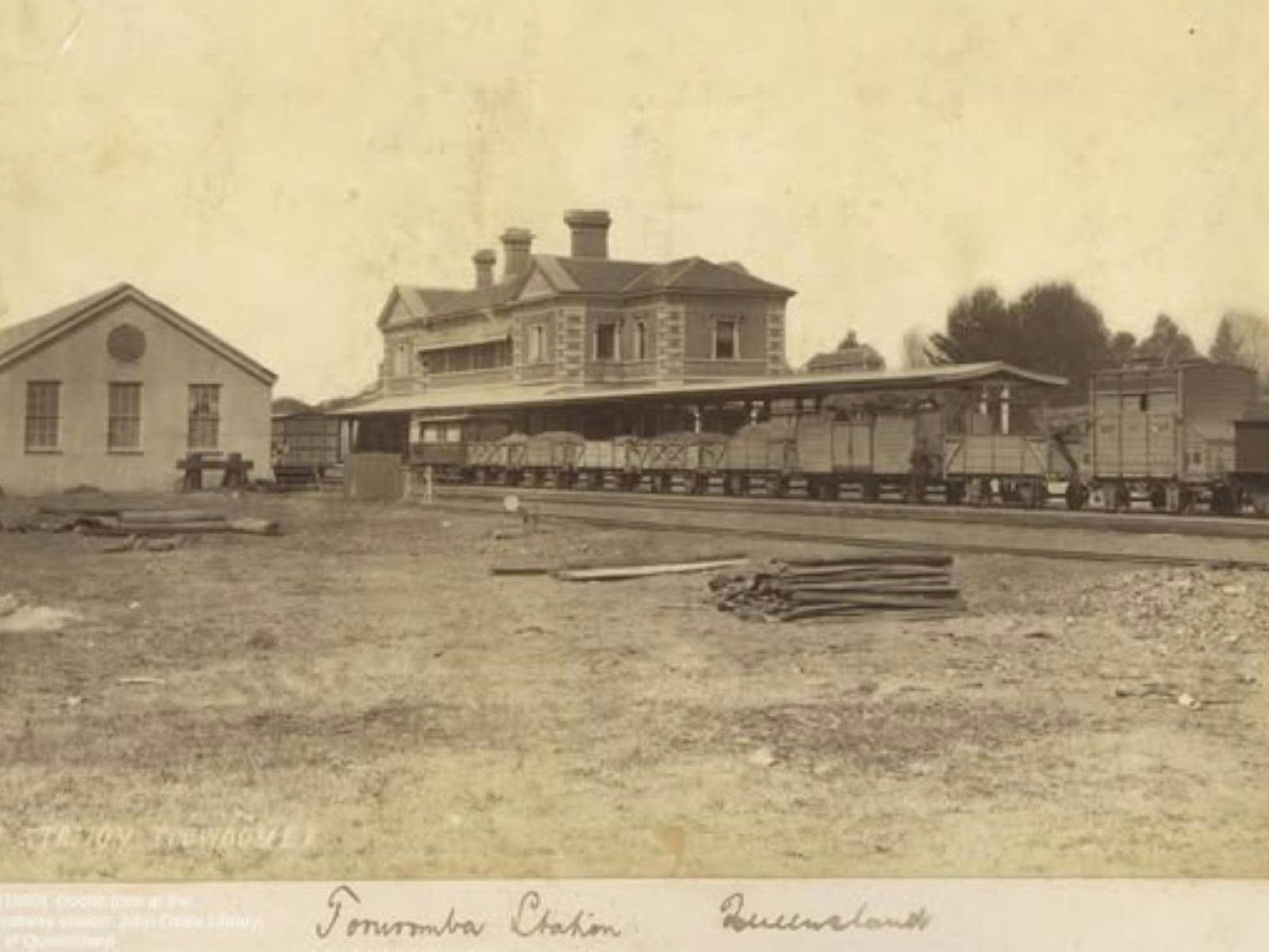 An old photo of a railway station in 1876, small rail carriages in the foreground An old photo of a railway station in 1876, small rail carriages in the foreground