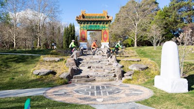 Three cyclists ride below the traditional Chinese gate