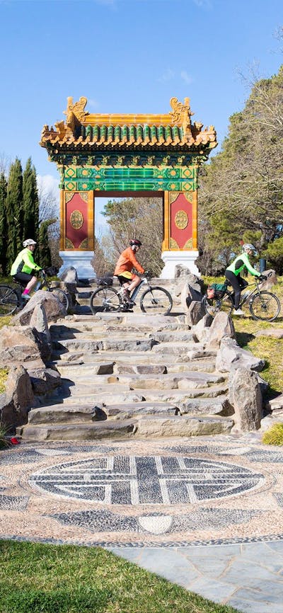 Three cyclists ride below the traditional Chinese gate
