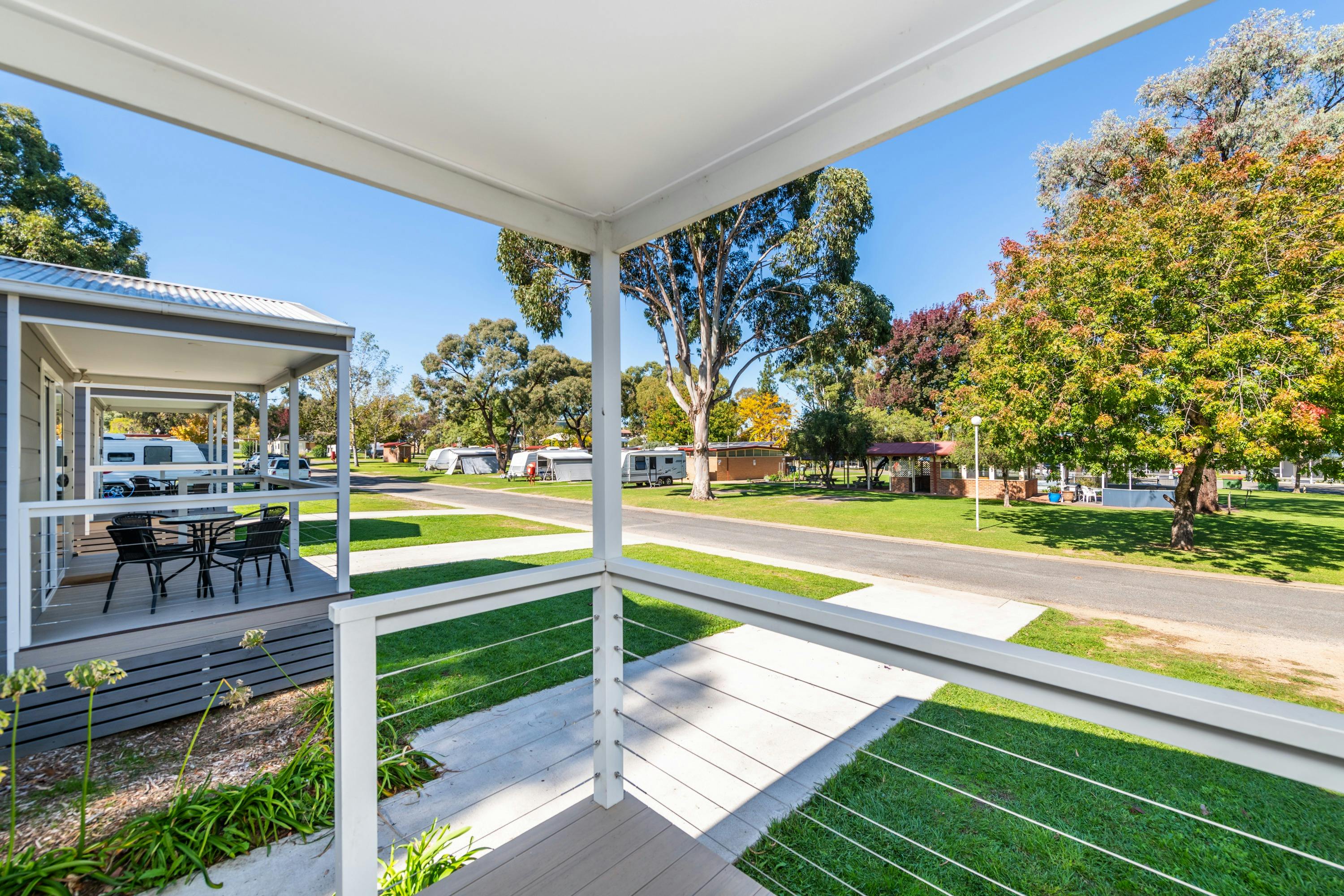View of caravan park from balcony of one of the cabins. A row of caravans parked across the road.