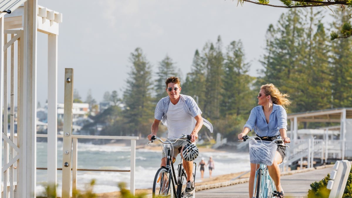2 people riding bikes along the water front