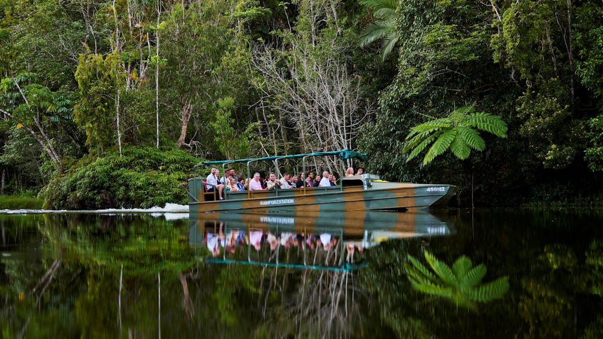 An amphibious Army Duck cruising on a lake amongst the rainforest, passengers enjoying the serenity