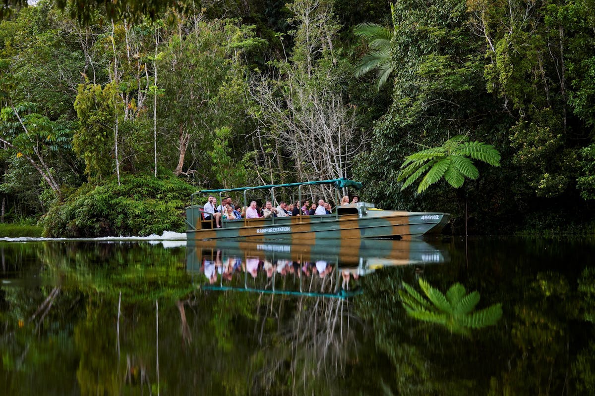 An amphibious Army Duck cruising on a lake amongst the rainforest, passengers enjoying the serenity