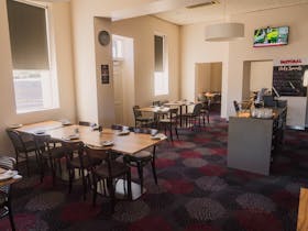 Pastoral Hotel Motel dining room with neatly arranged tables and bright natural light.