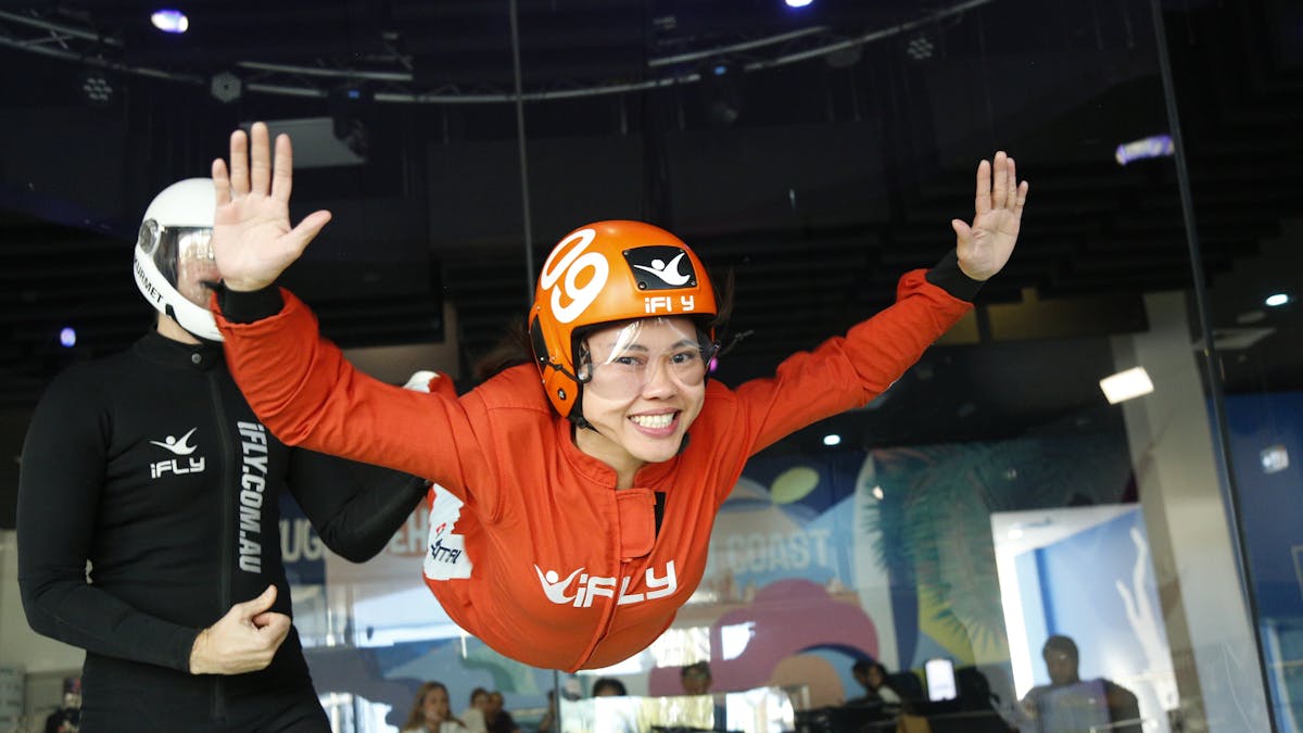 Female first time flyer in an orange suit with a massive smile.