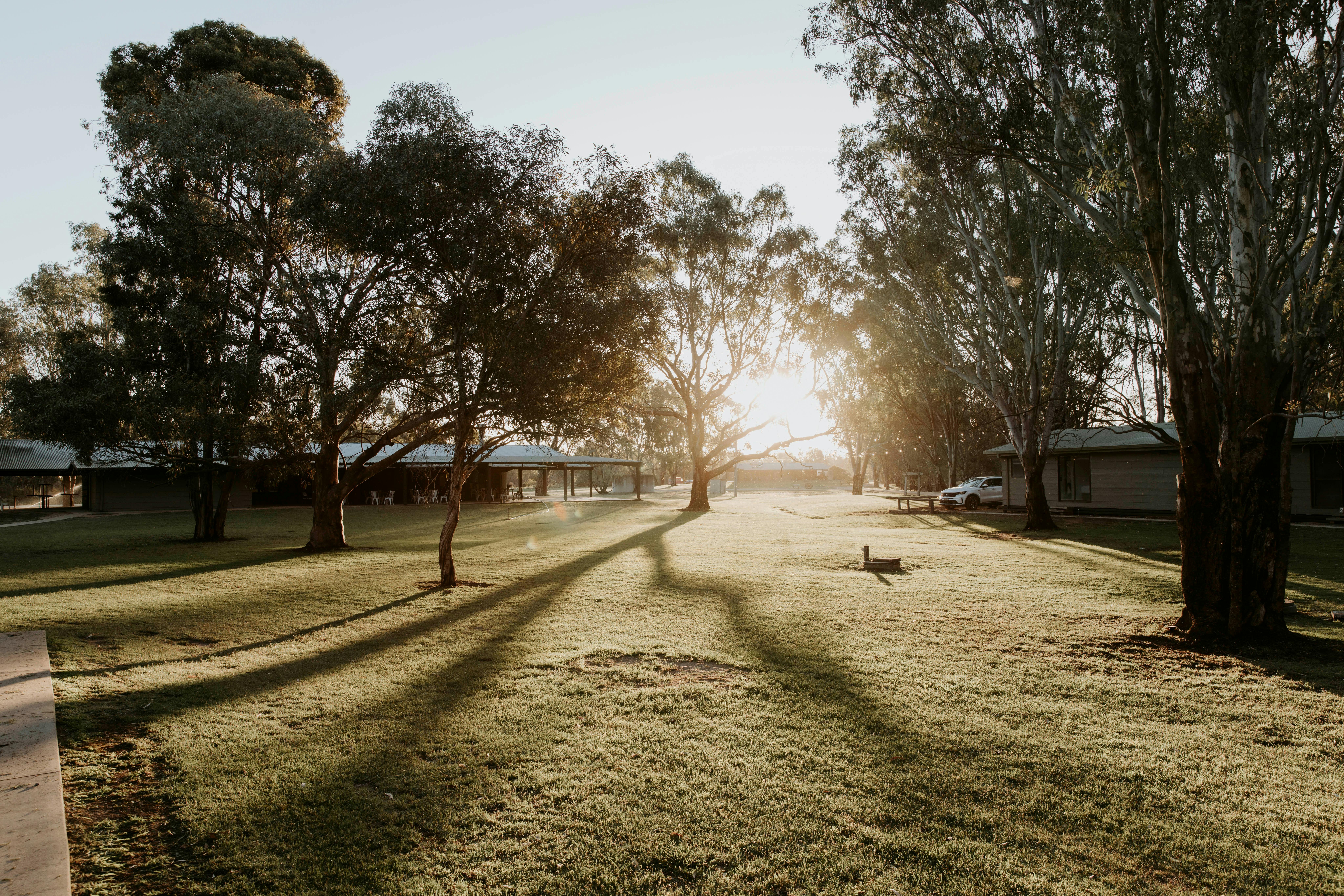 The sun setting over the lawn between the cabins at The Paddock at Ulupna