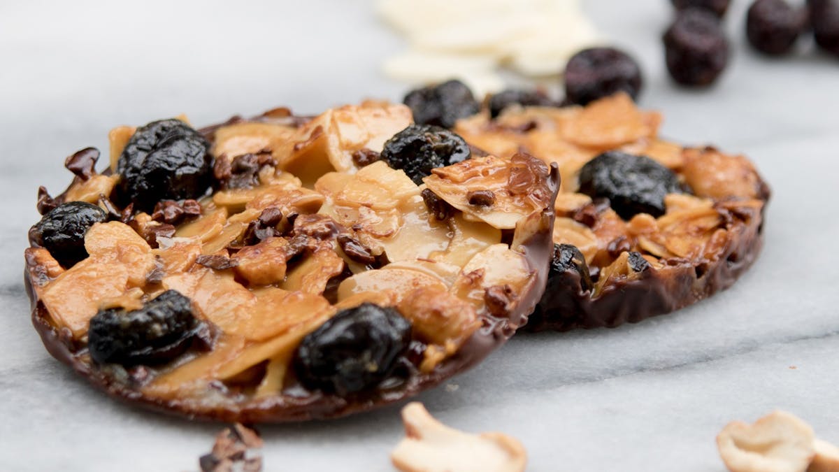 Two nut and caramel cookies with scattered ingredients