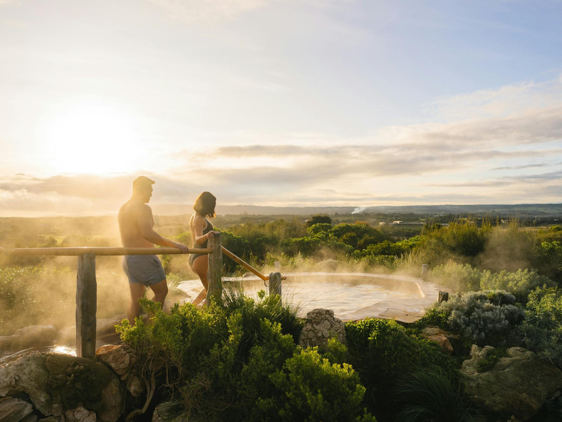 Two people stepping into a hot spring pool
