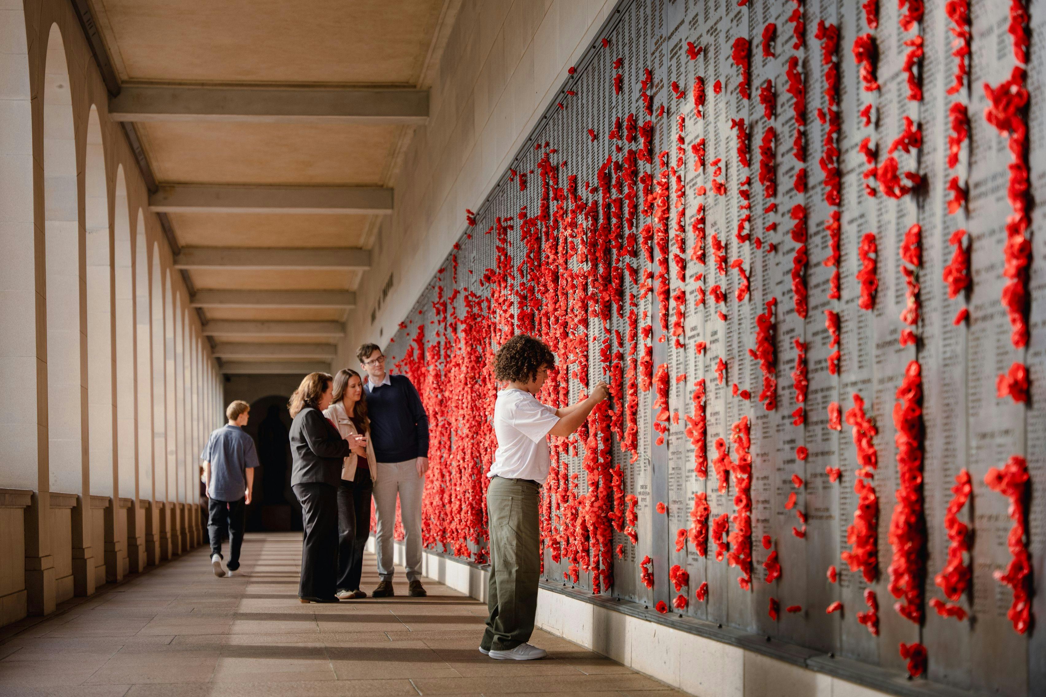 Visitors standing in front of wall of red poppies