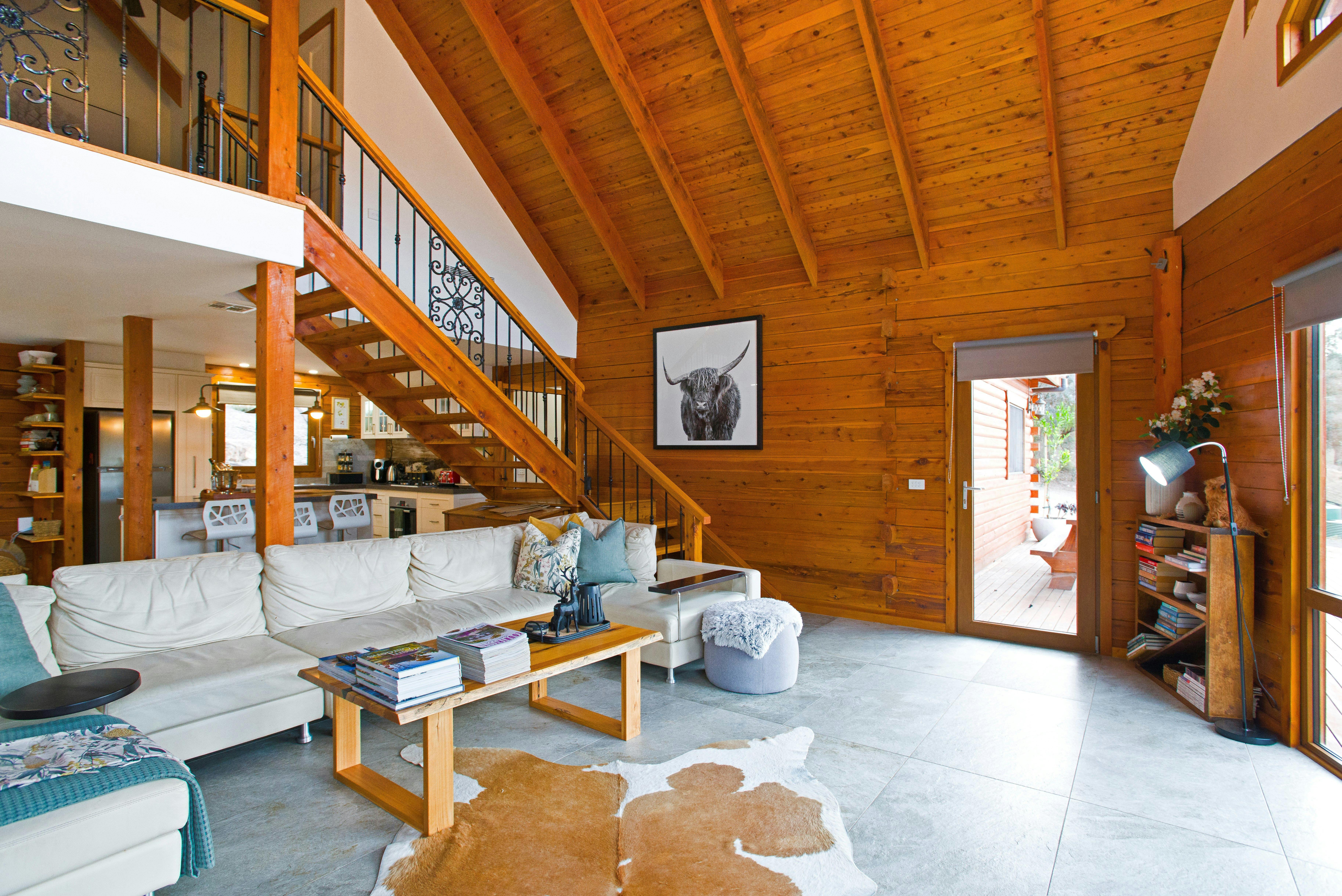 Living room with timber ceilings, bookcase, and large sectional lounge.
