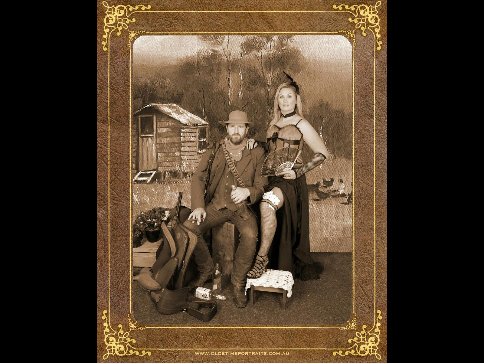 a couple dressed in western costume, saloon girl, acubra hats with background of old pickers hut Tas