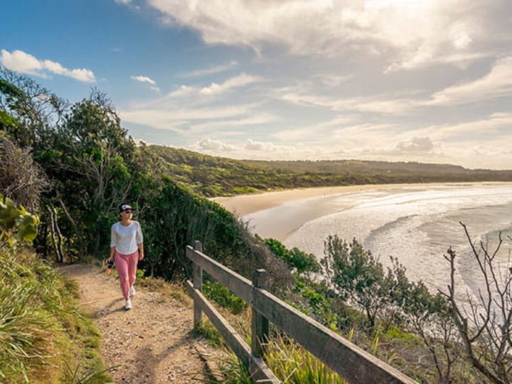 Woman walking along Three Sisters walking track, overlooking the beach in Broken Head Nature Reserve