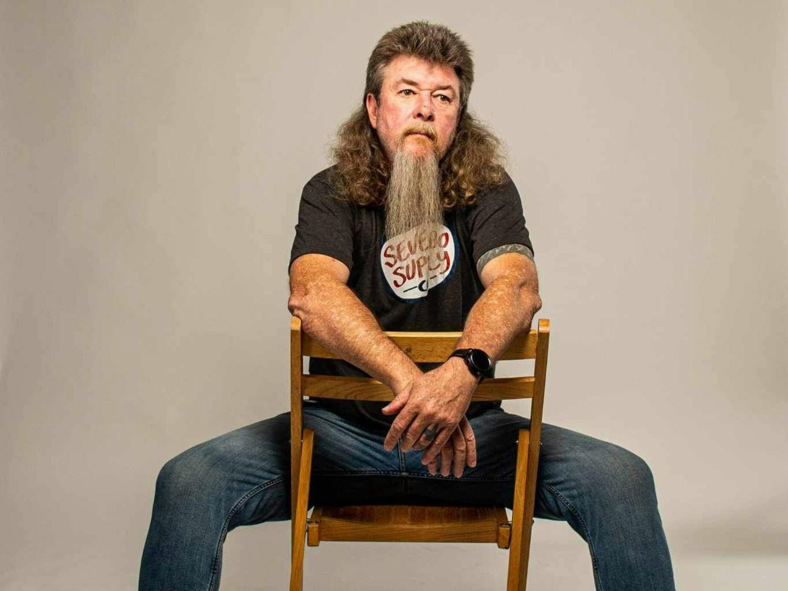 A man with a beard sitting on a chair.