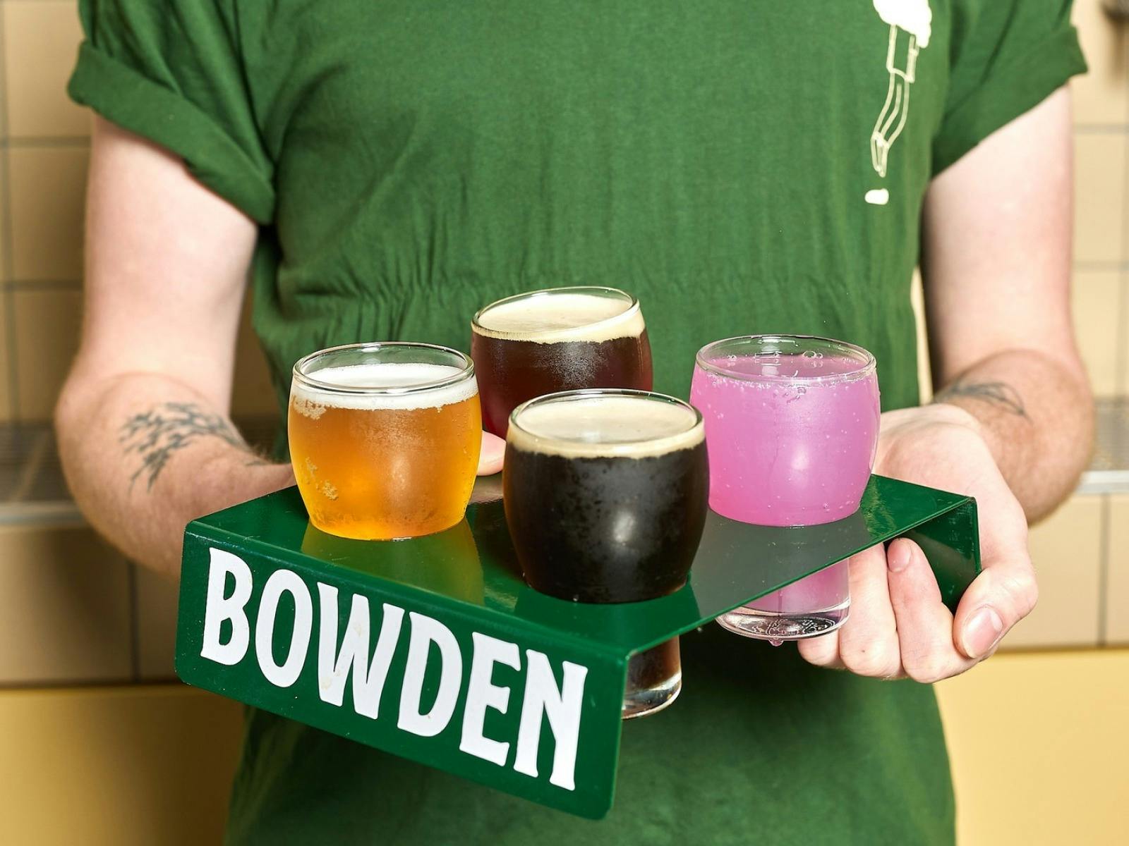 Person holds green tray with 4 beers in glasses