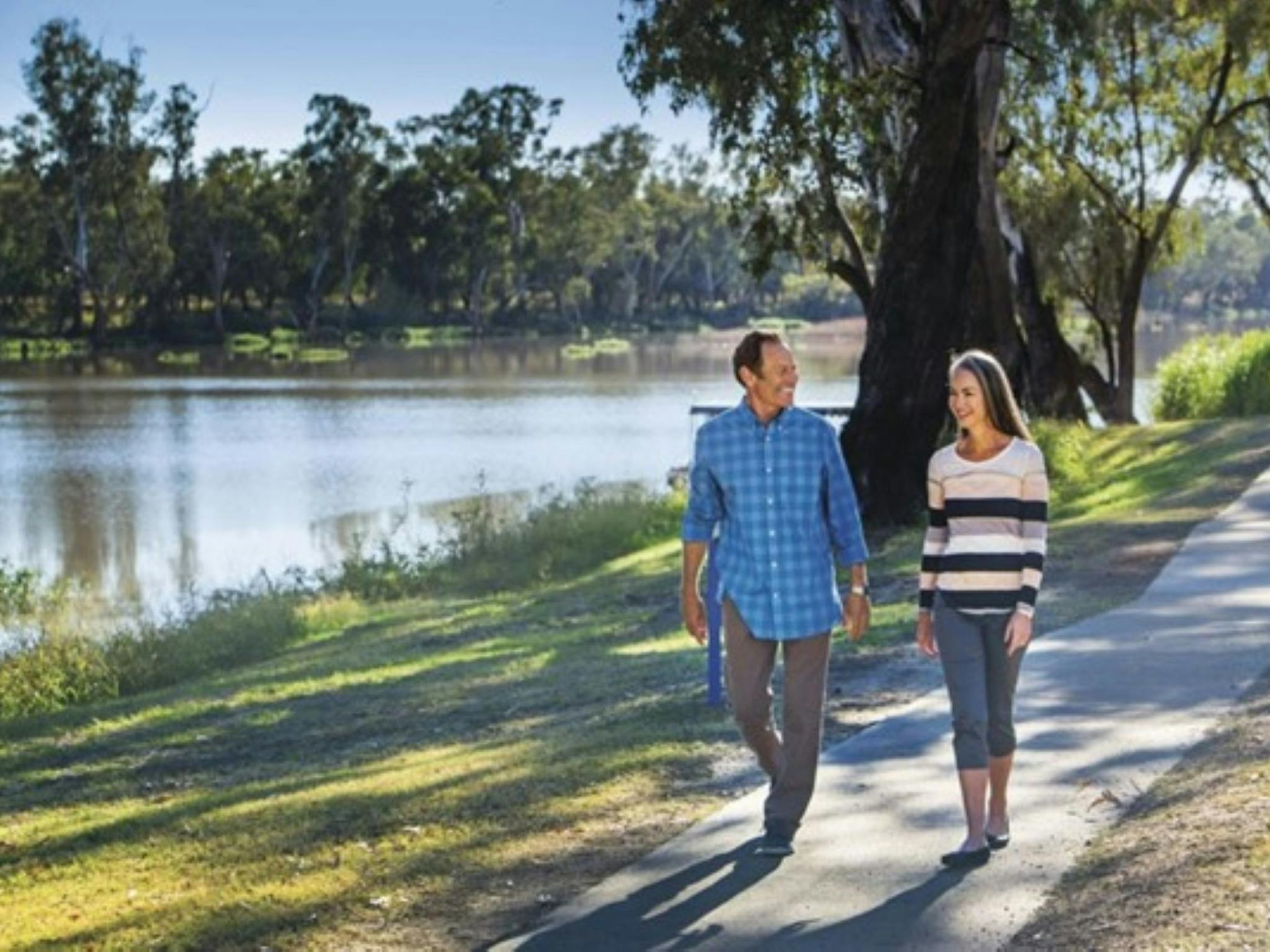 Man and Woman walking along a path next to a river Man and Woman walking along a path next to a river