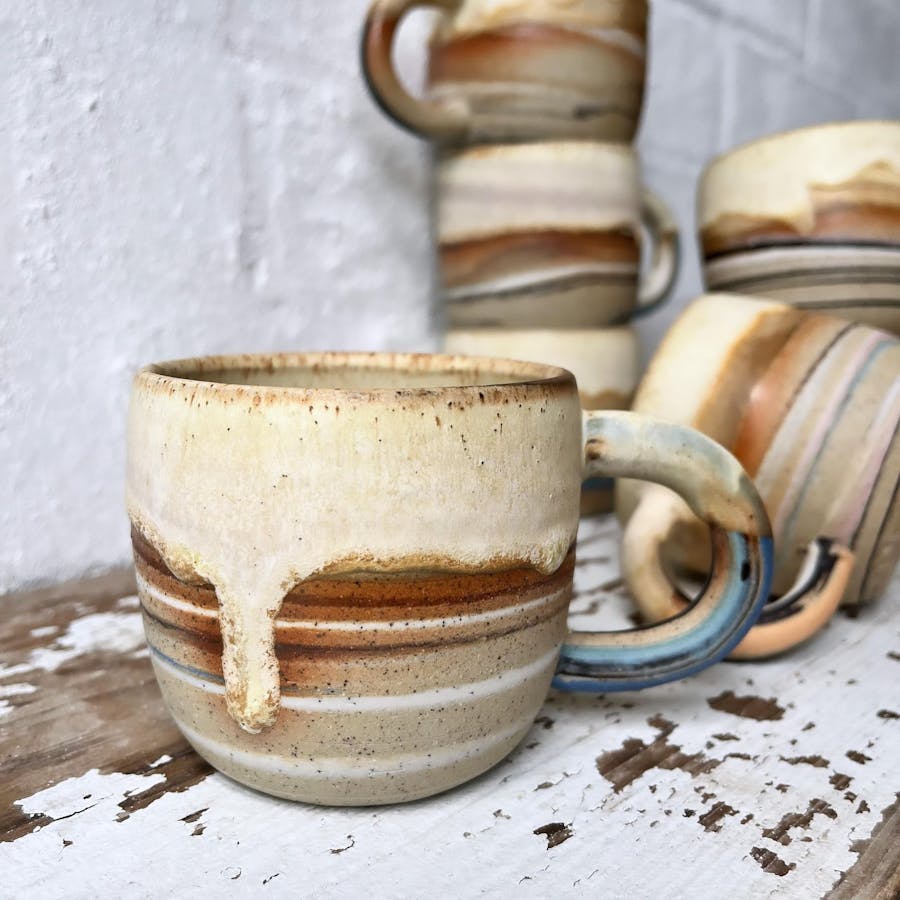 a collection of stripey cups with drippy glaze