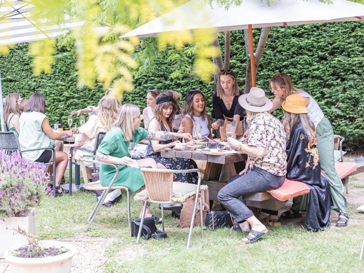 A group of ladies enjoying cheese and wine in an outdoor garden