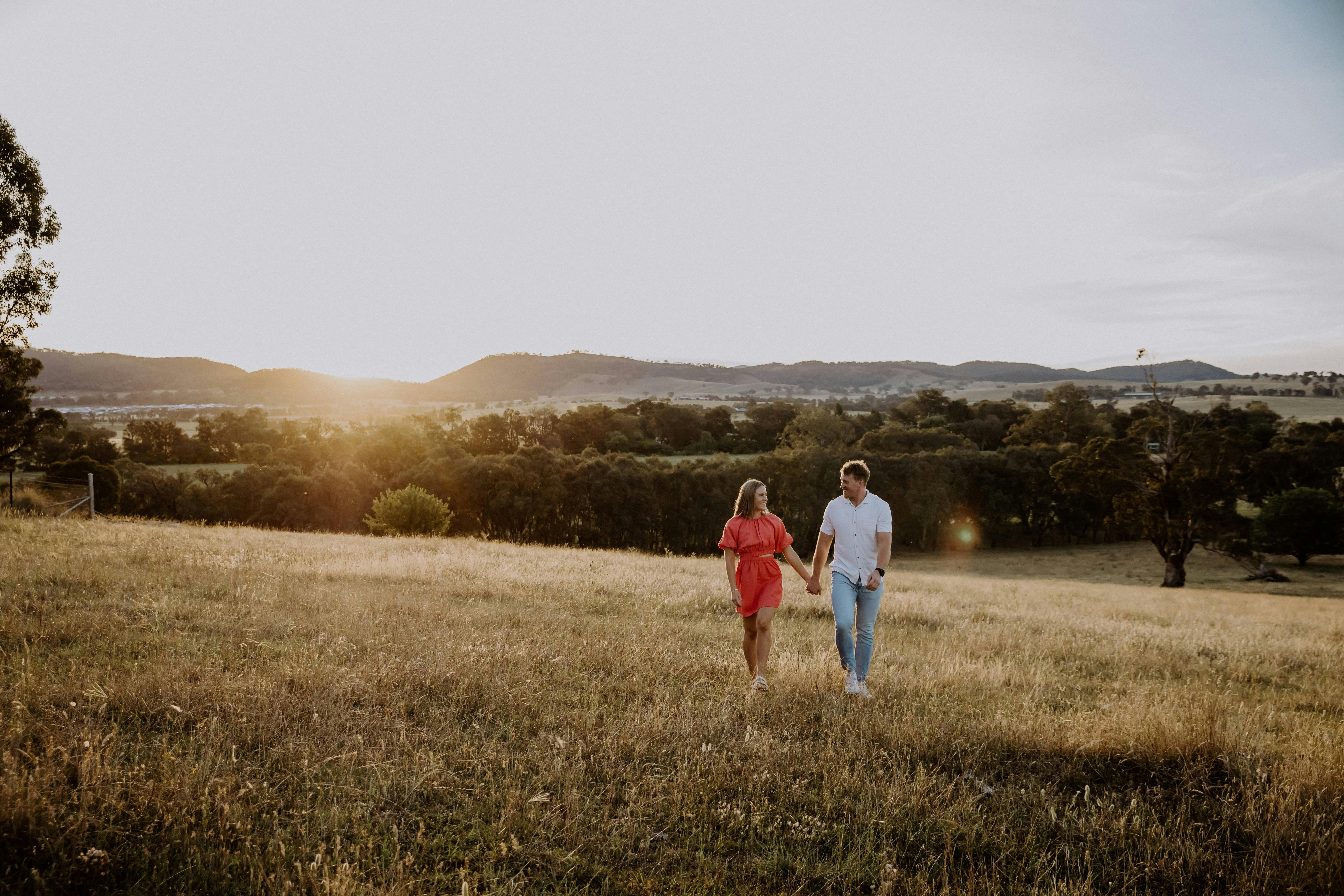 Sun setting in the hills couple walking through the paddock