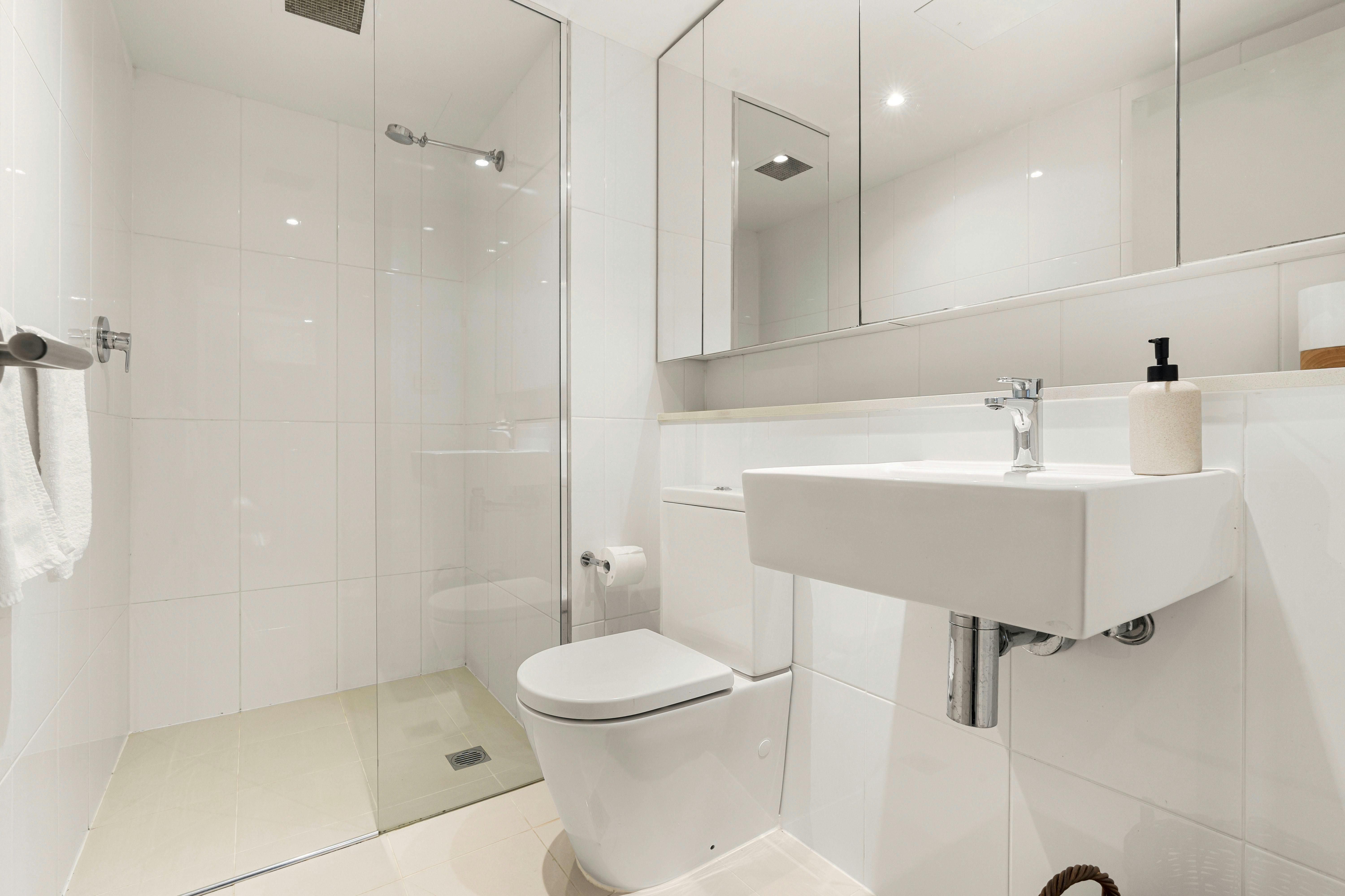 Contemporary bathroom featuring a shower, modern sink, and clean white tiles.