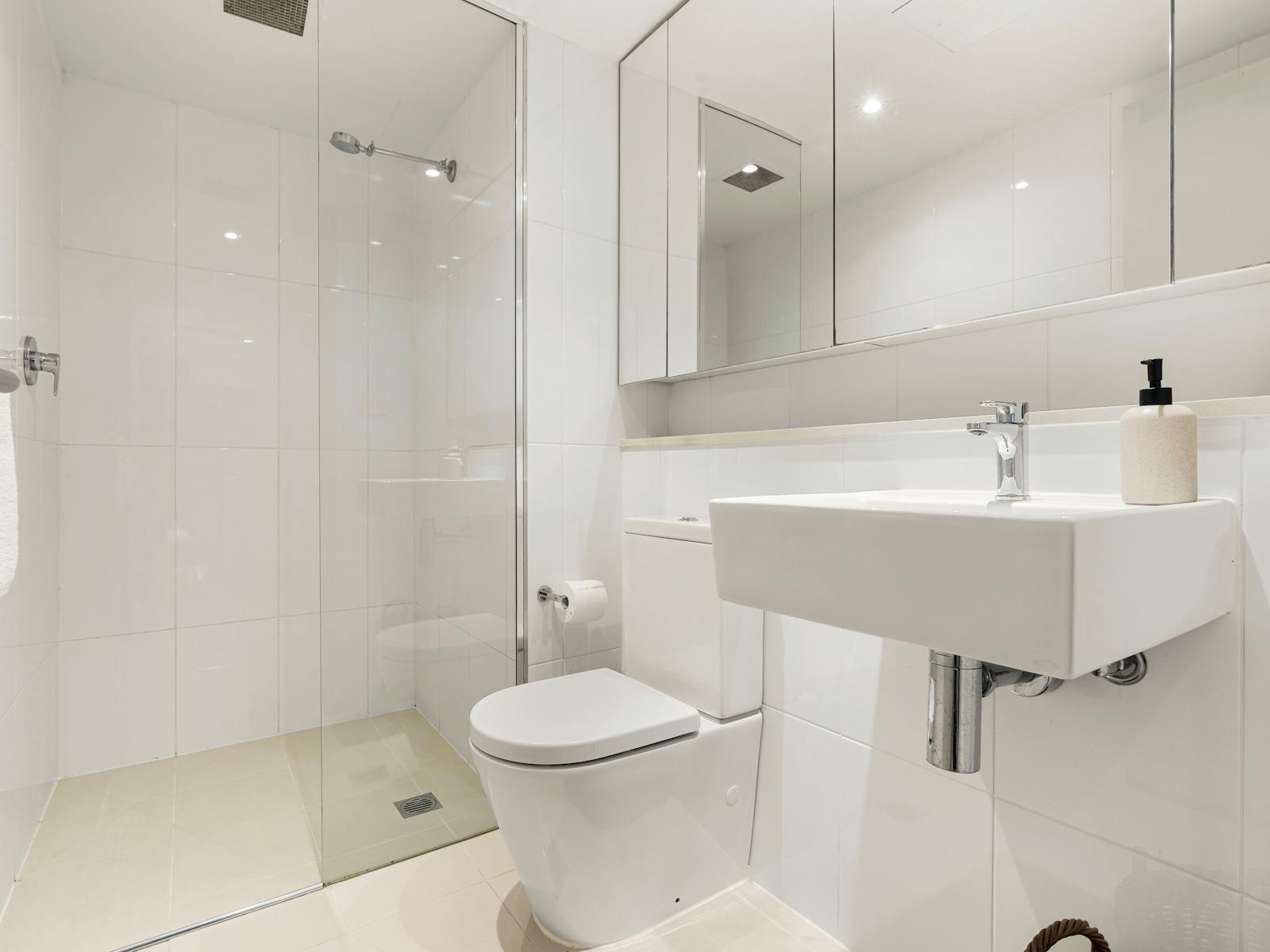 Contemporary bathroom featuring a shower, modern sink, and clean white tiles.
